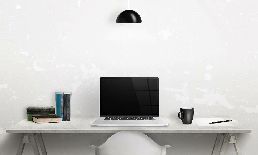 An uncluttered desk with a white marbled wall in the background.