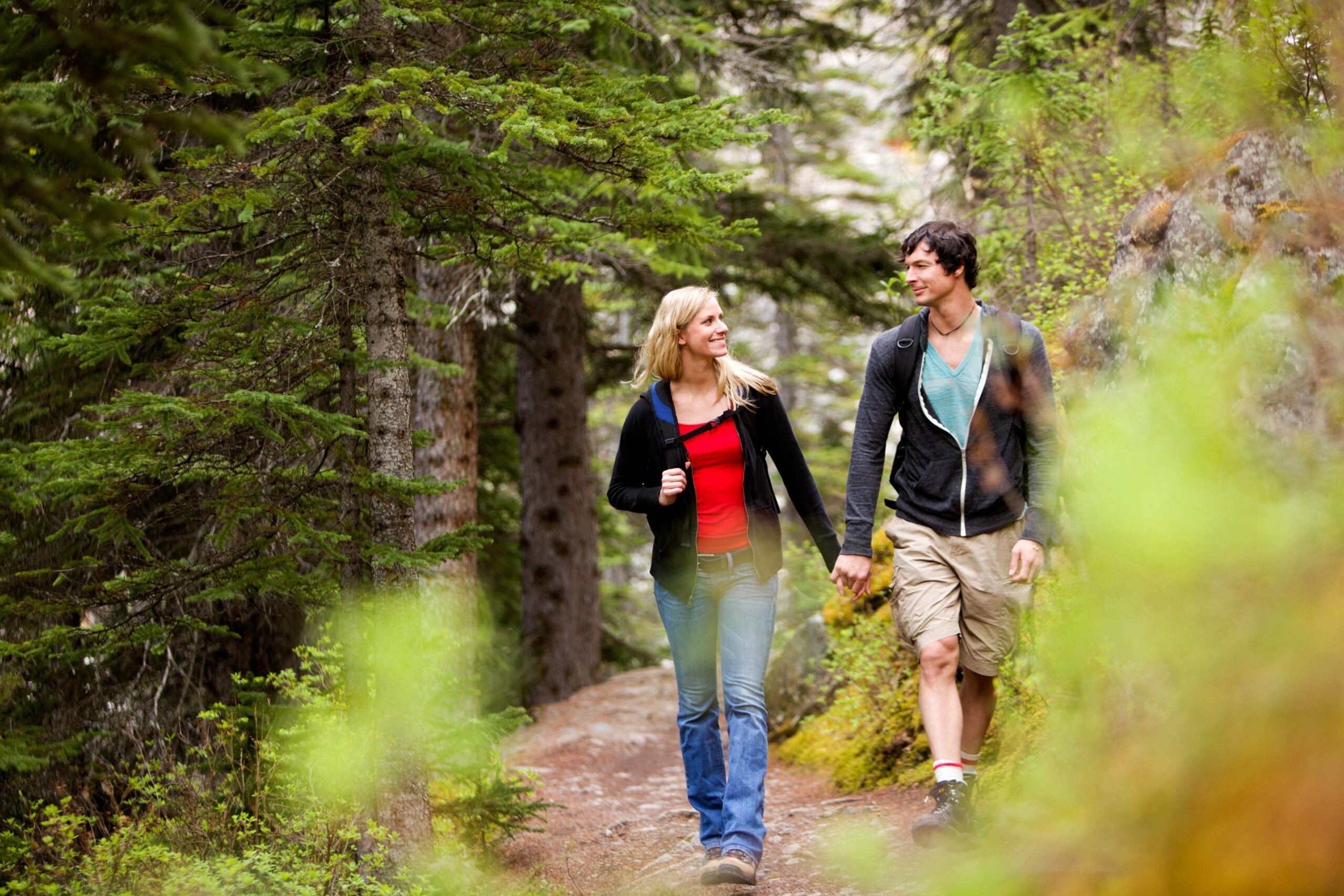 happy couple hiking on a trail in wooded area