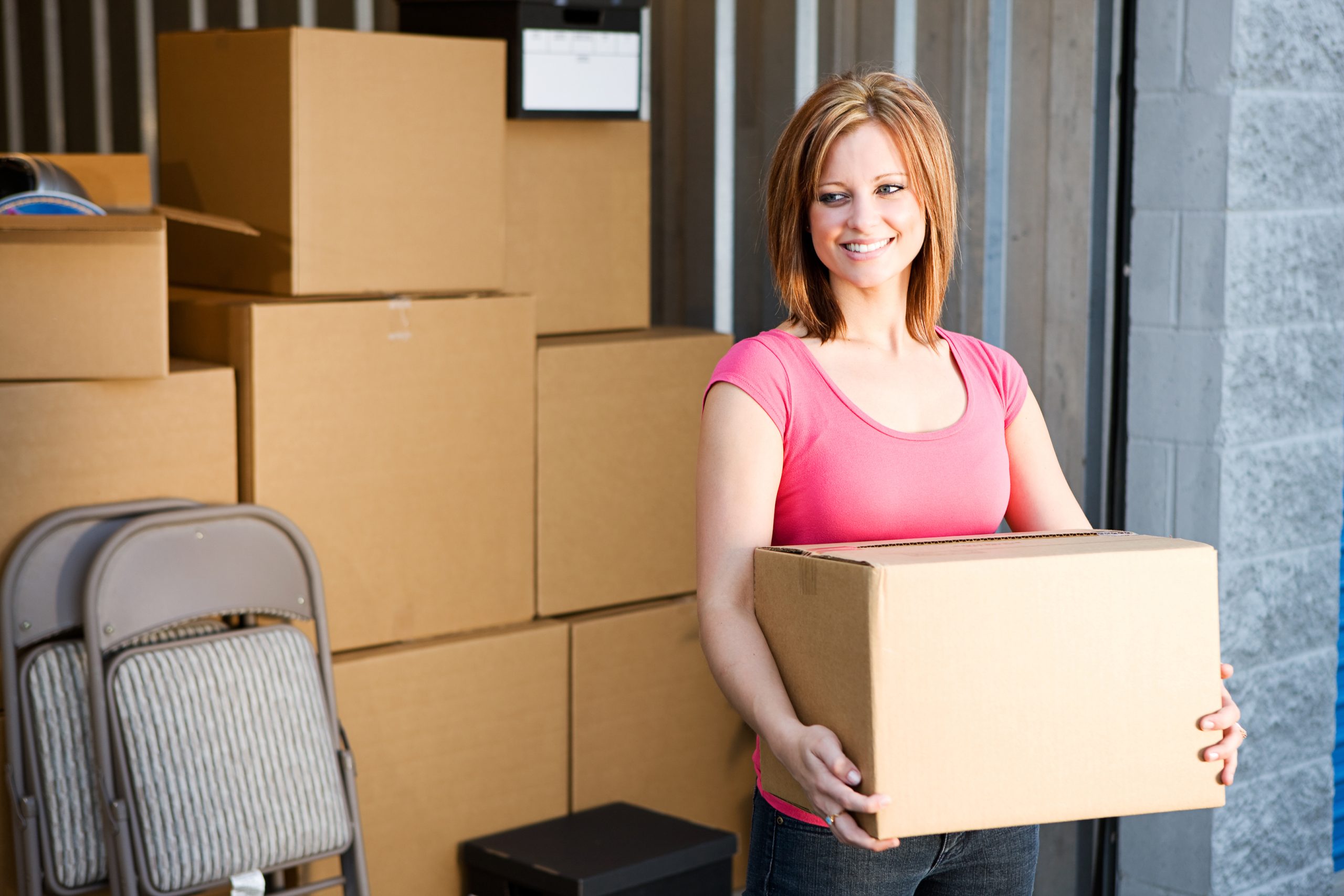 Woman holding box and coming out of storage unit