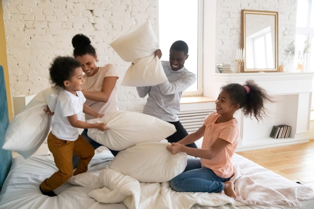 african american family having a pillow fight on a mattress