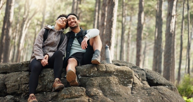 cute couple sitting on rock while in the forest