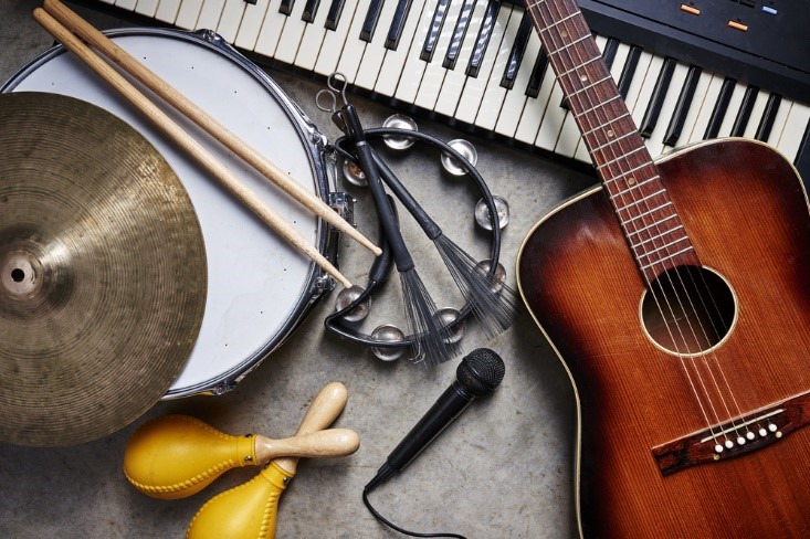 group of instruments on the floor including a guitar, piano, drum sticks