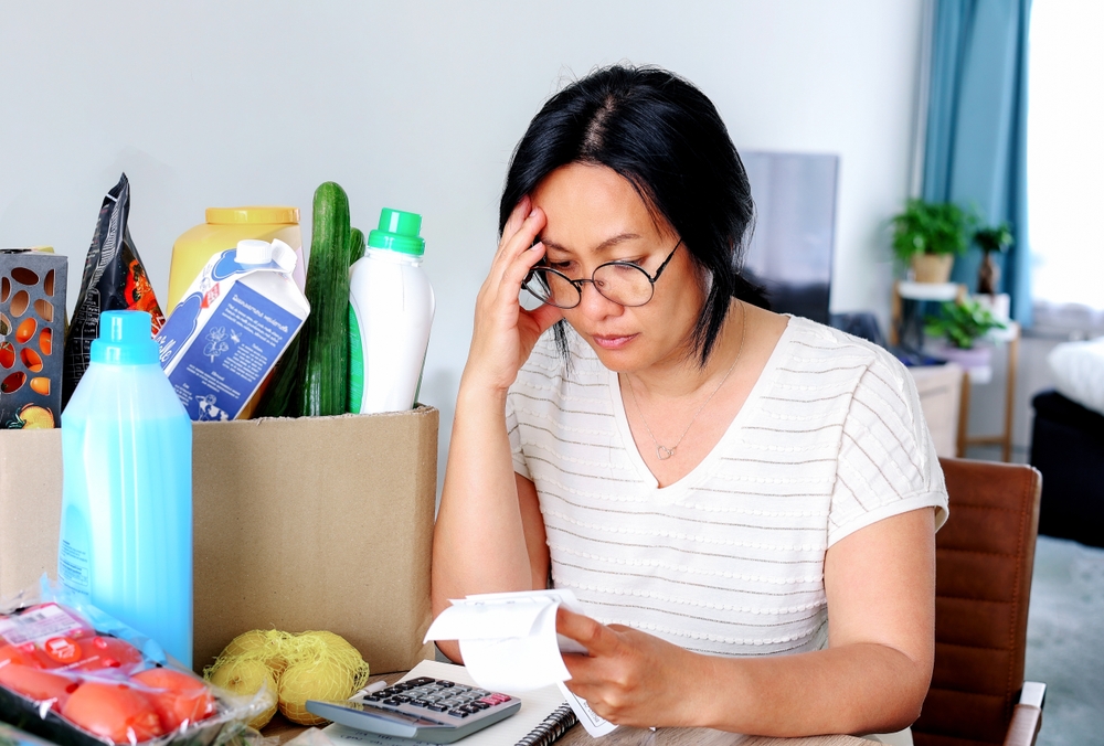 Woman looking at bills and expenses next to box of various items